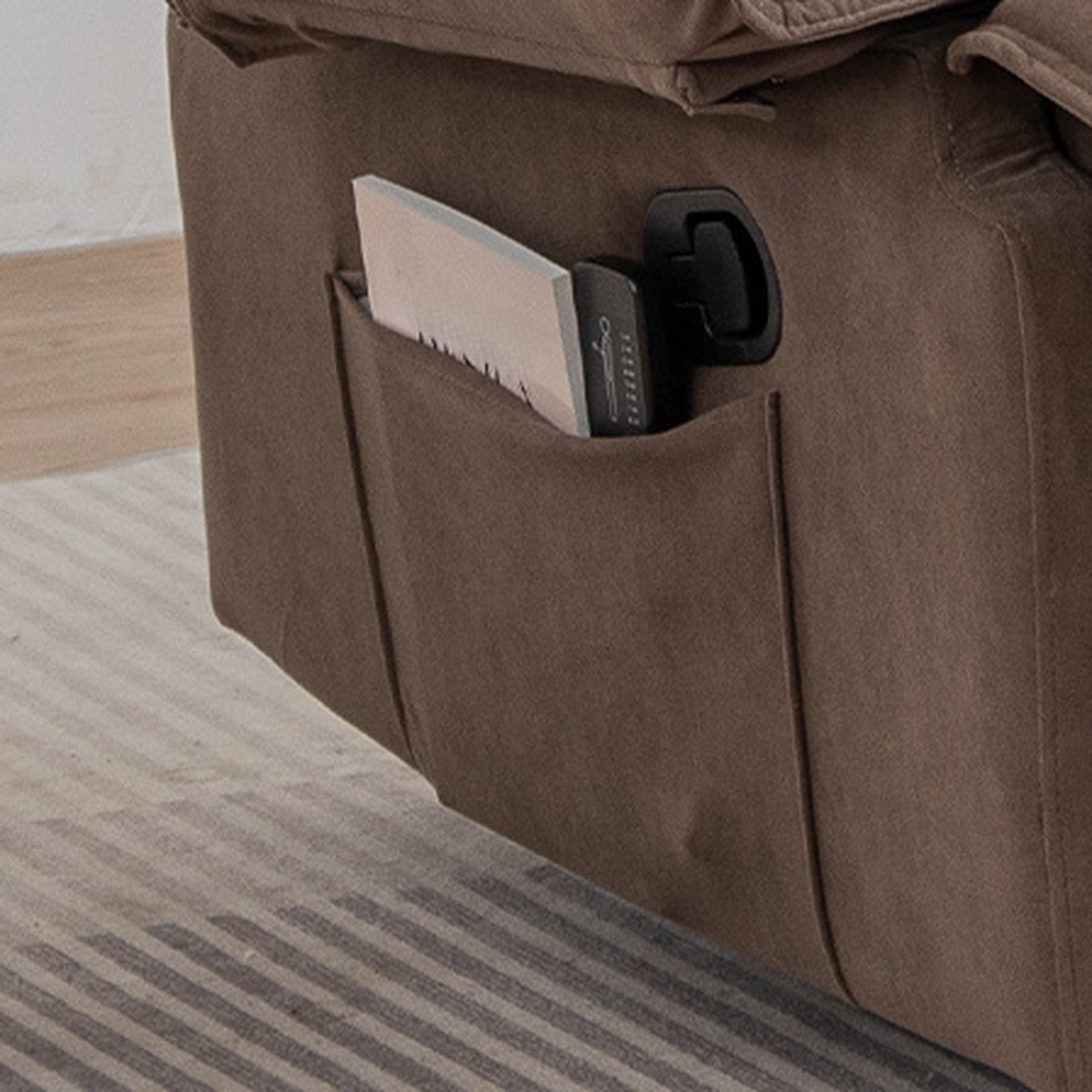 Brown fabric recliner with side pocket holding book and remote control