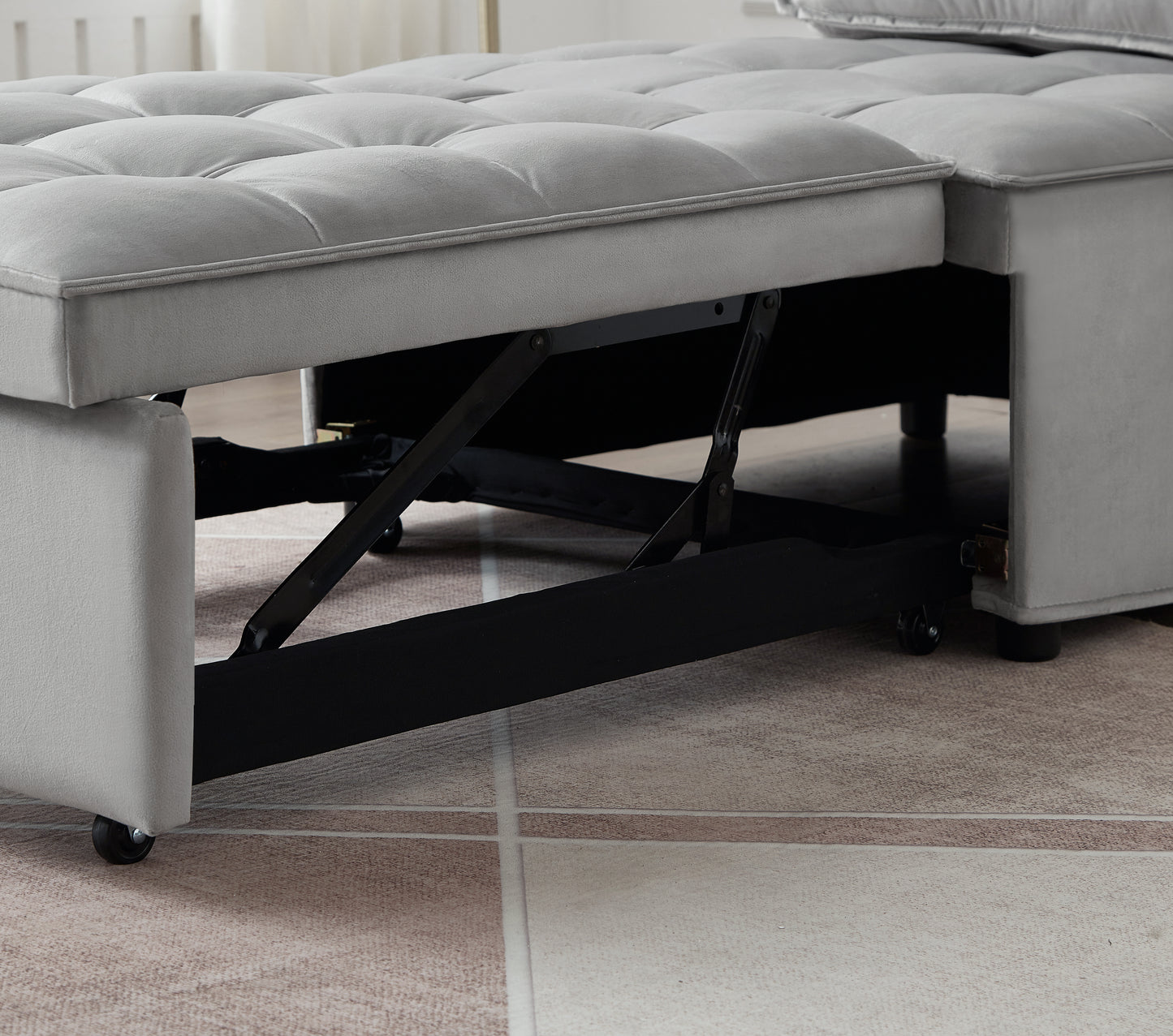 Grey velvet sofa bed with tufted cushions and visible metal mechanism for conversion