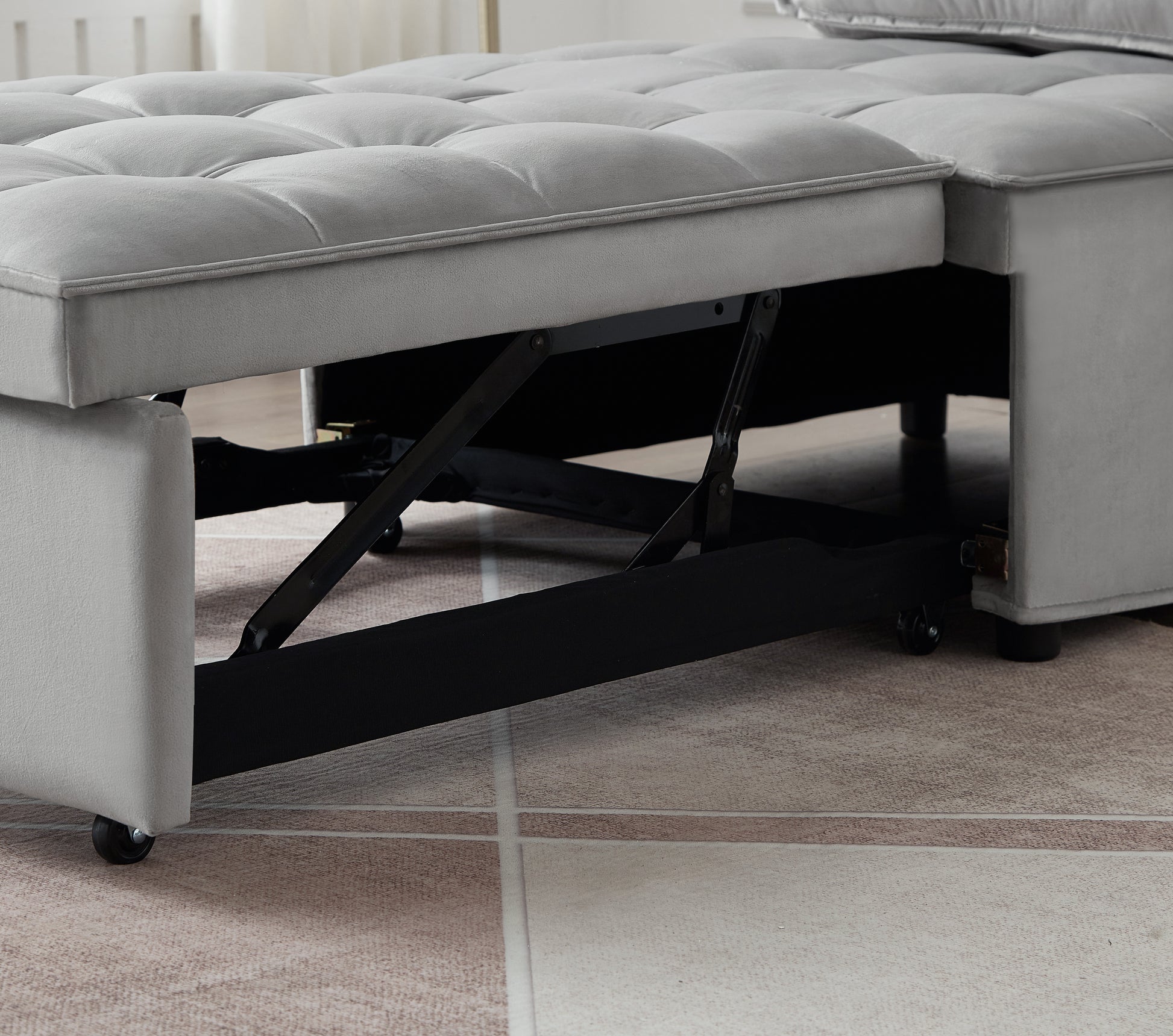 Grey velvet sofa bed with tufted cushions and visible metal mechanism for conversion