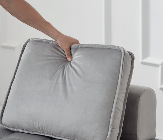 Light gray velvet couch pillow with tufted detail and piping