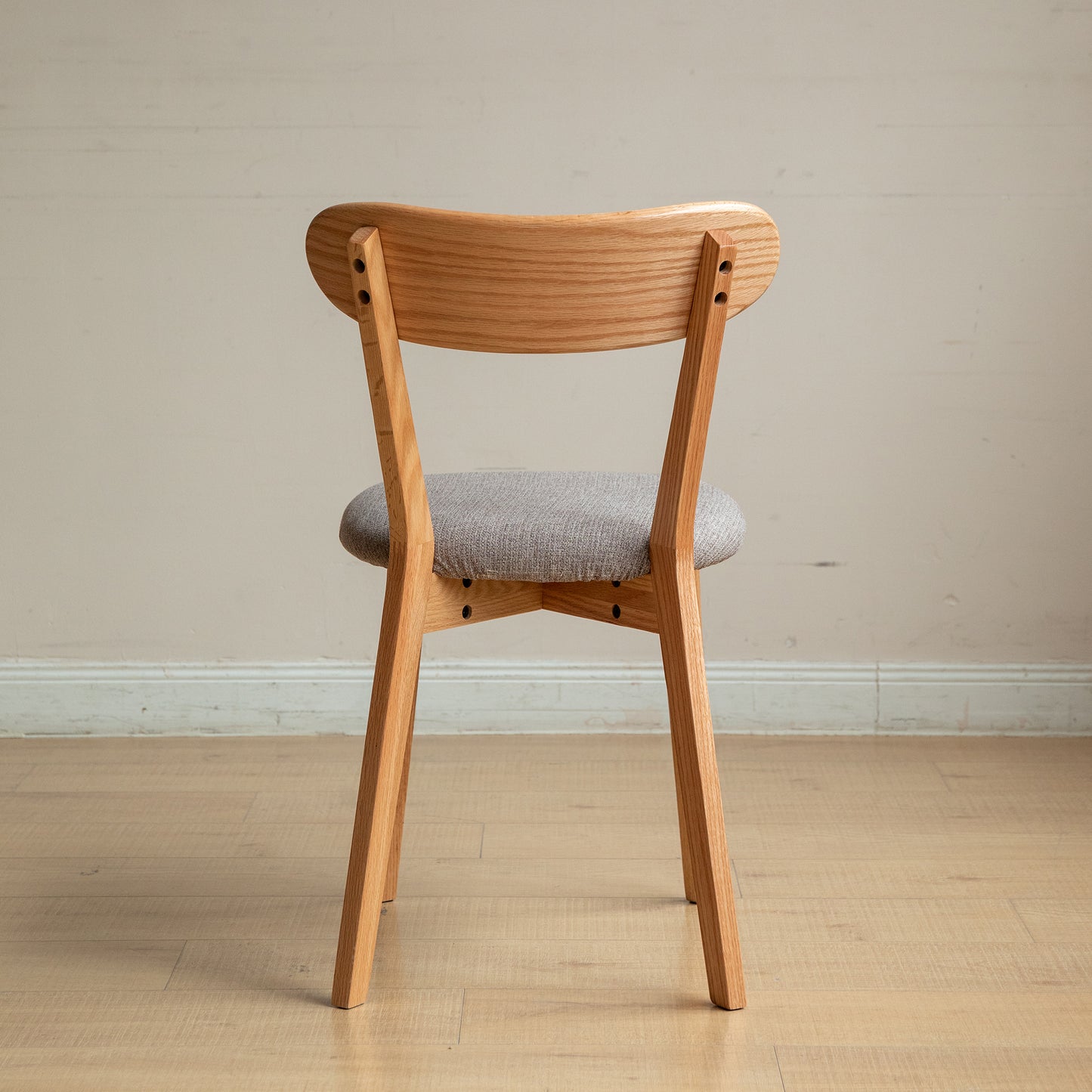 Wooden dining chair with curved back and grey upholstered seat