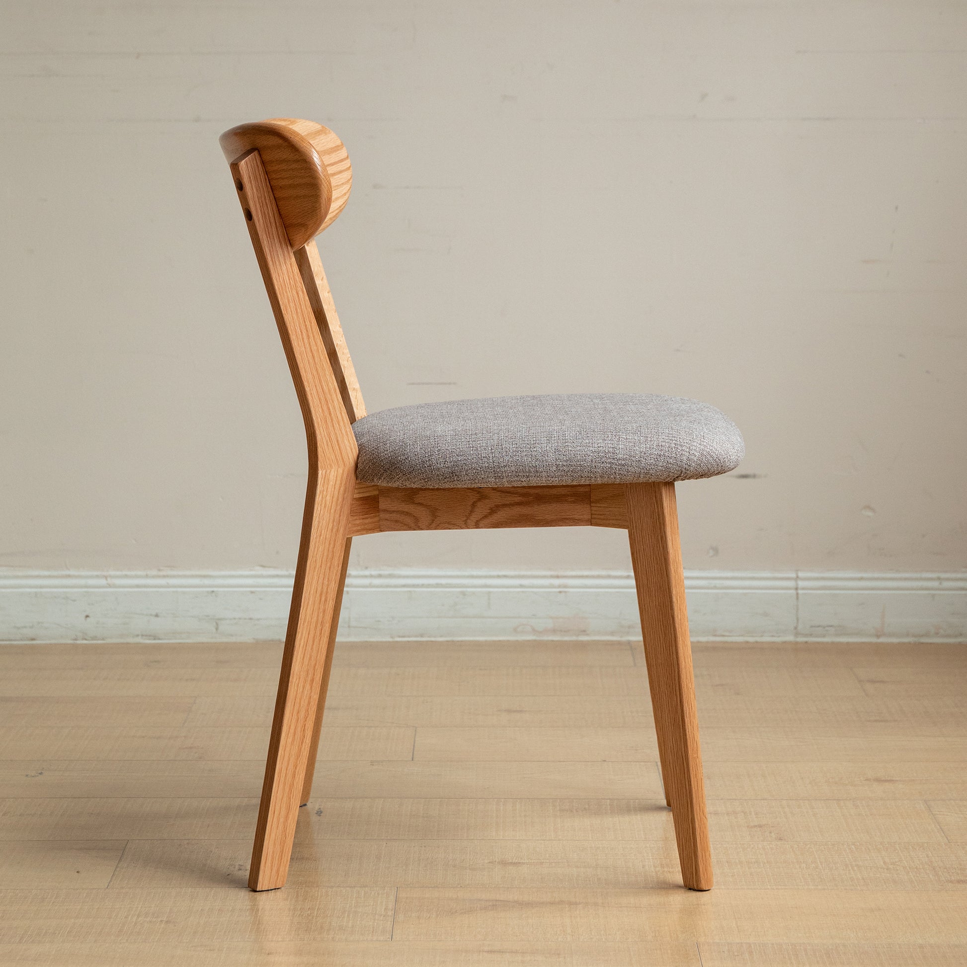 Wooden dining chair with light grey fabric seat and curved backrest