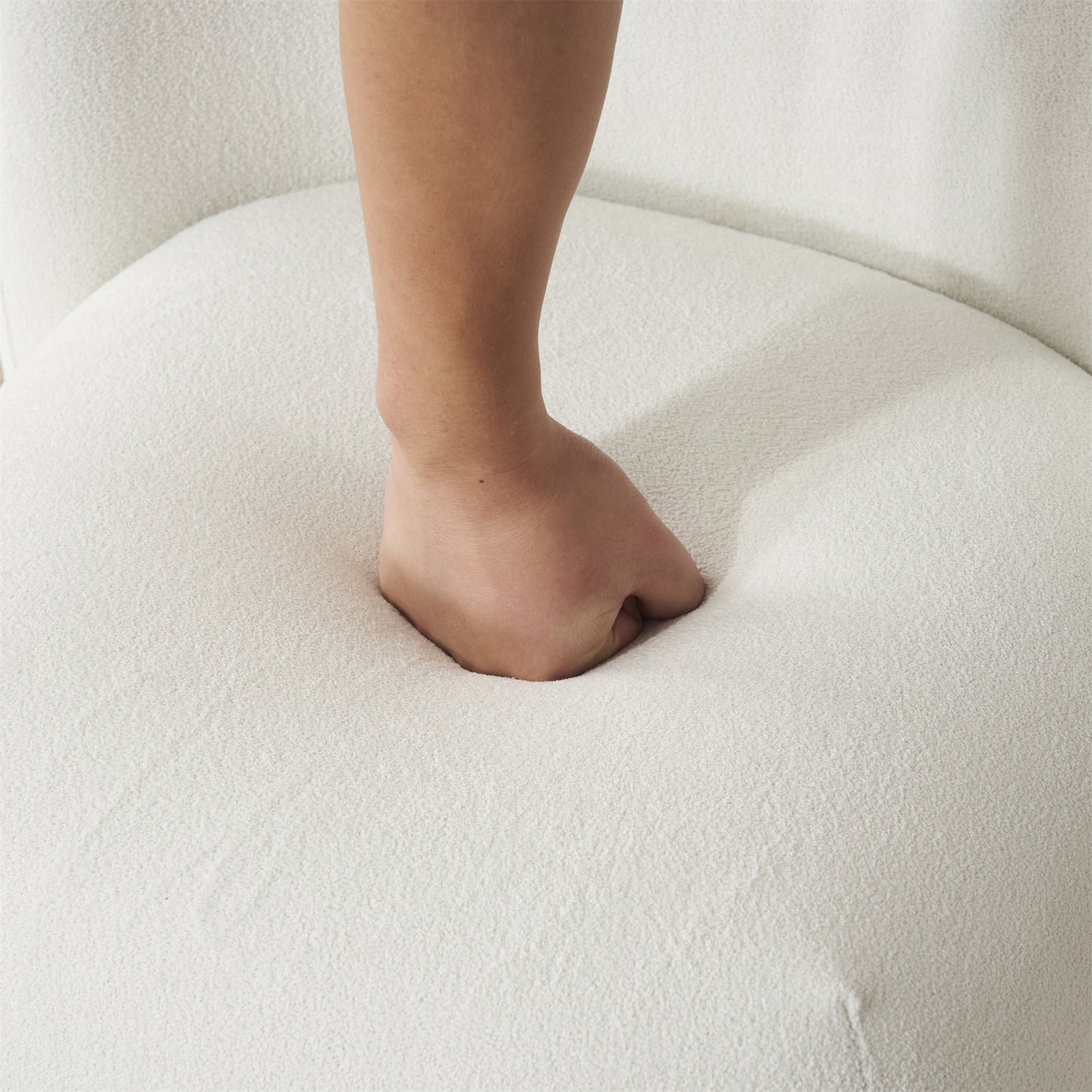 Closeup of hand pressing into plush white armchair cushion