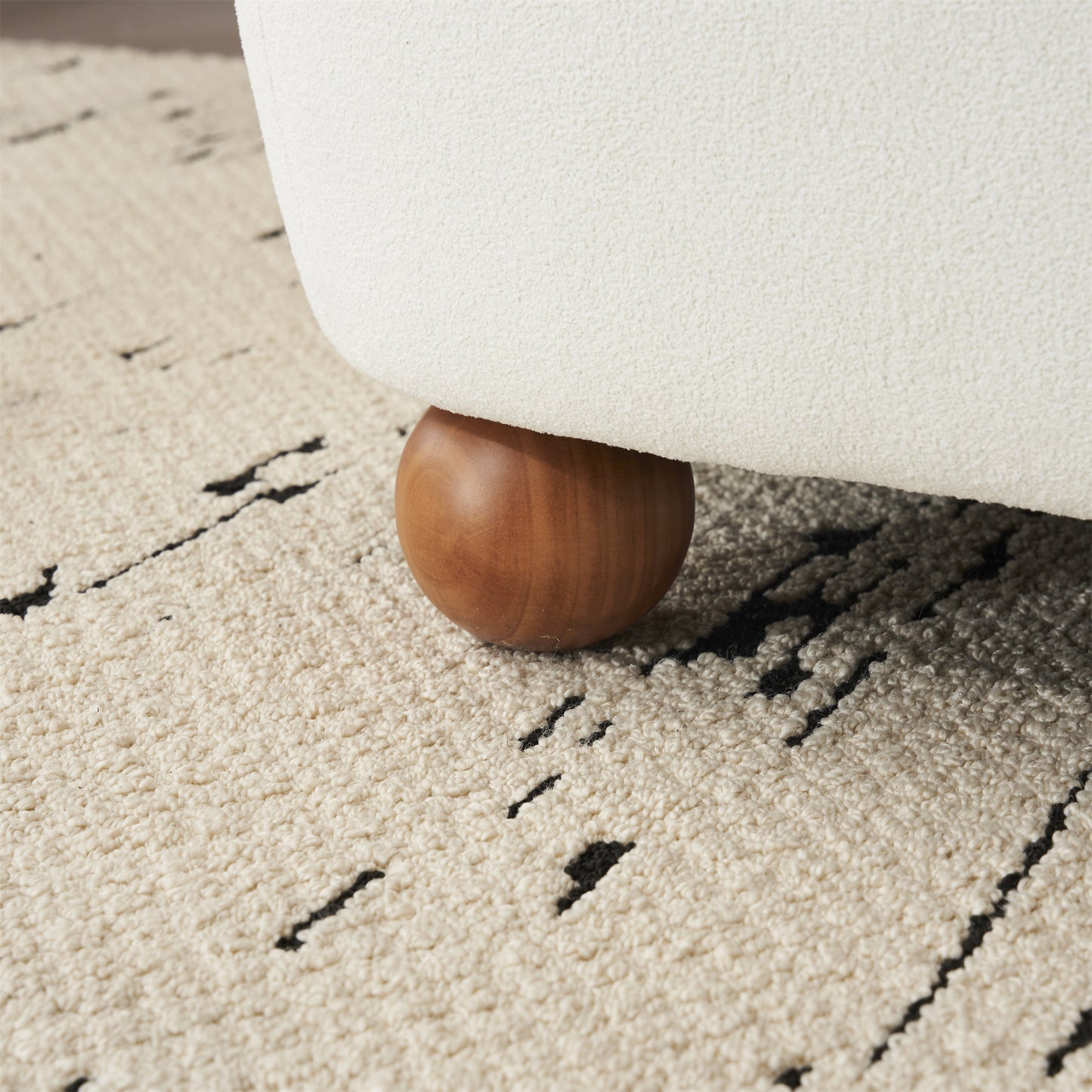Cream boucle armchair leg detail with natural wood foot