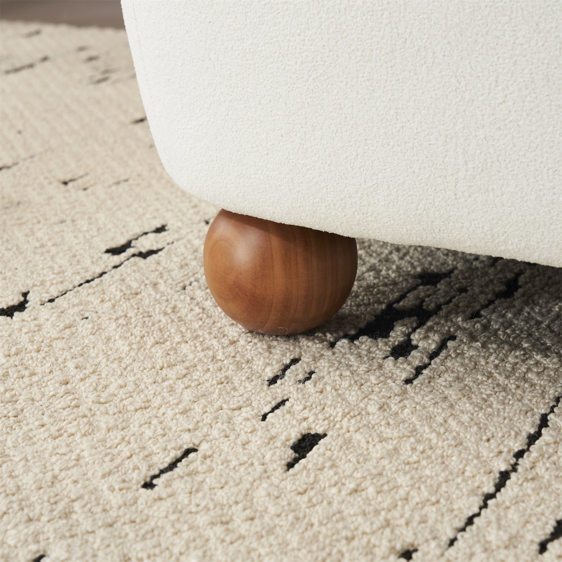Cream boucle armchair leg detail with natural wood foot
