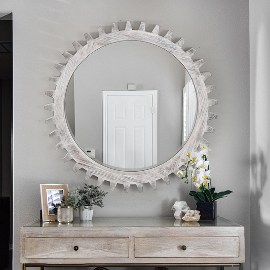 Round white wood gear frame mirror reflecting a white door