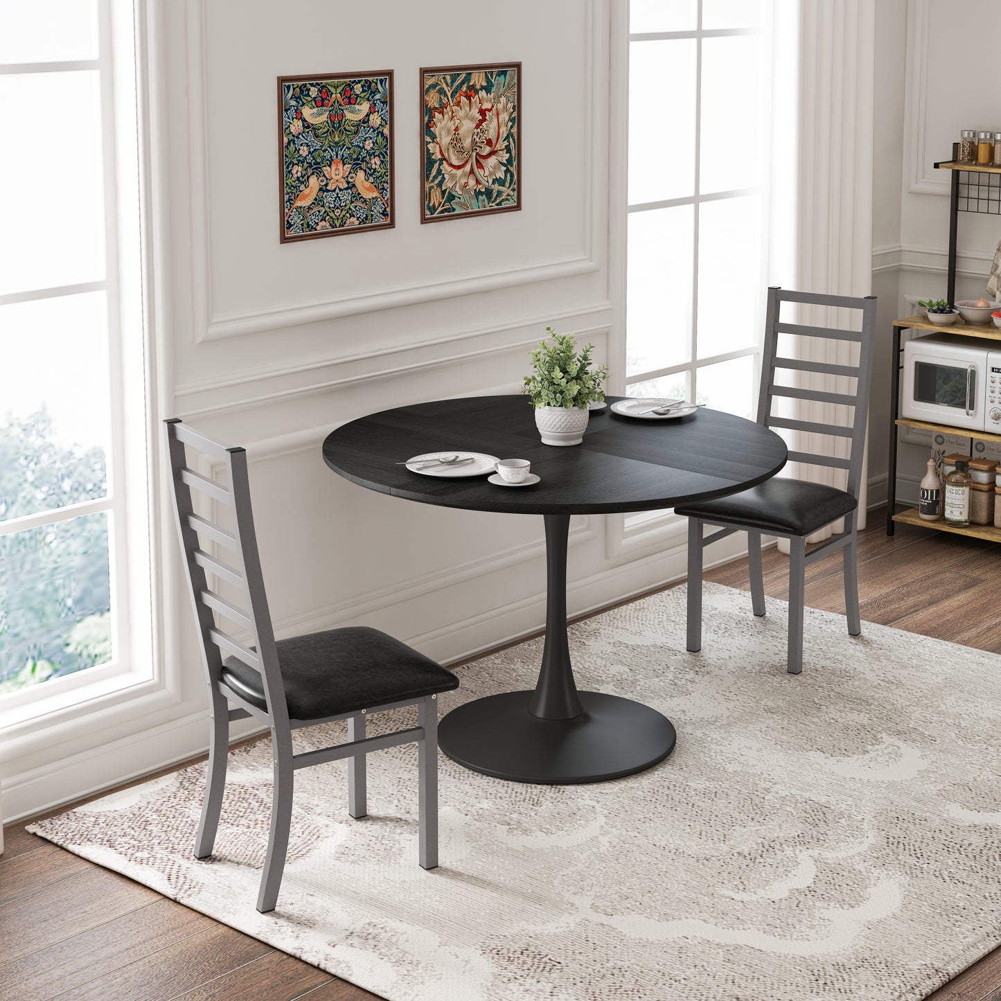 Black round pedestal dining table with two gray metal chairs