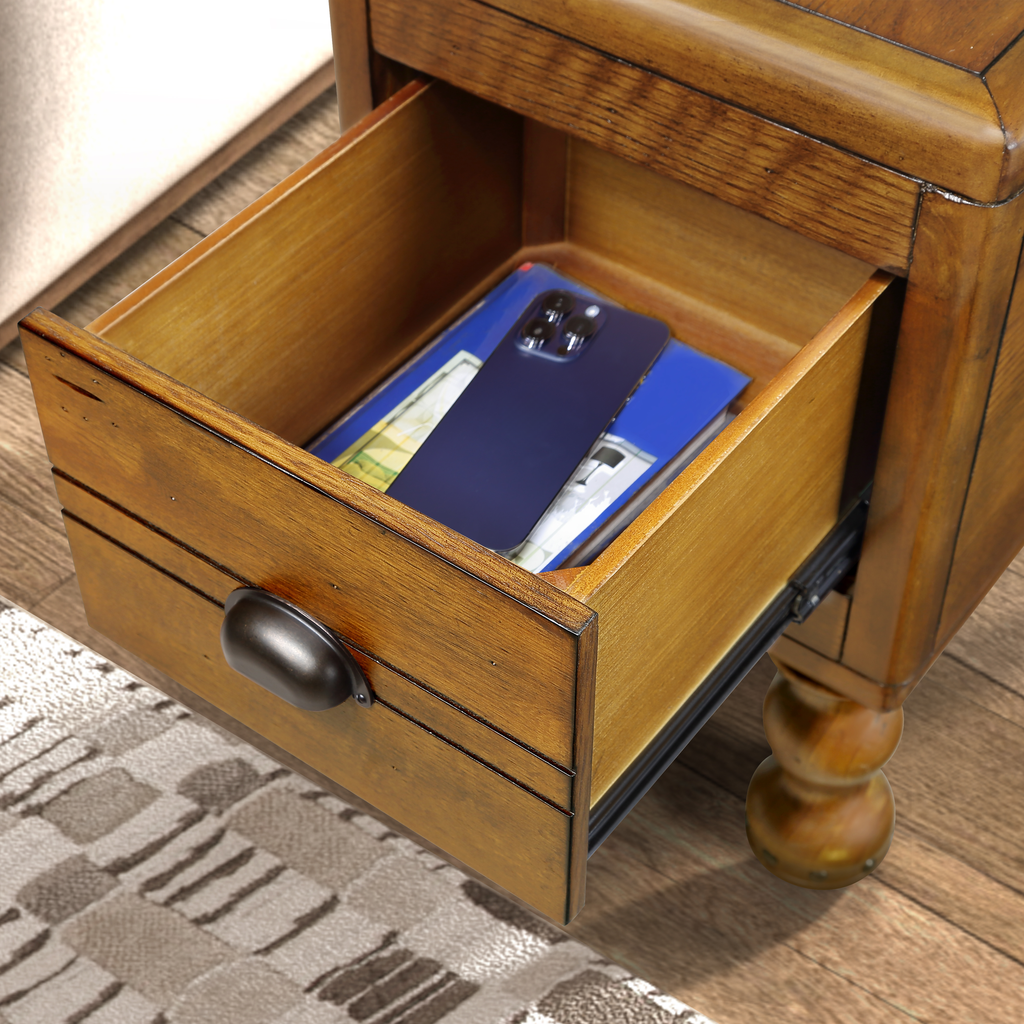 Open rustic oak nightstand drawer with a dark bronze pull holding a phone and blue book