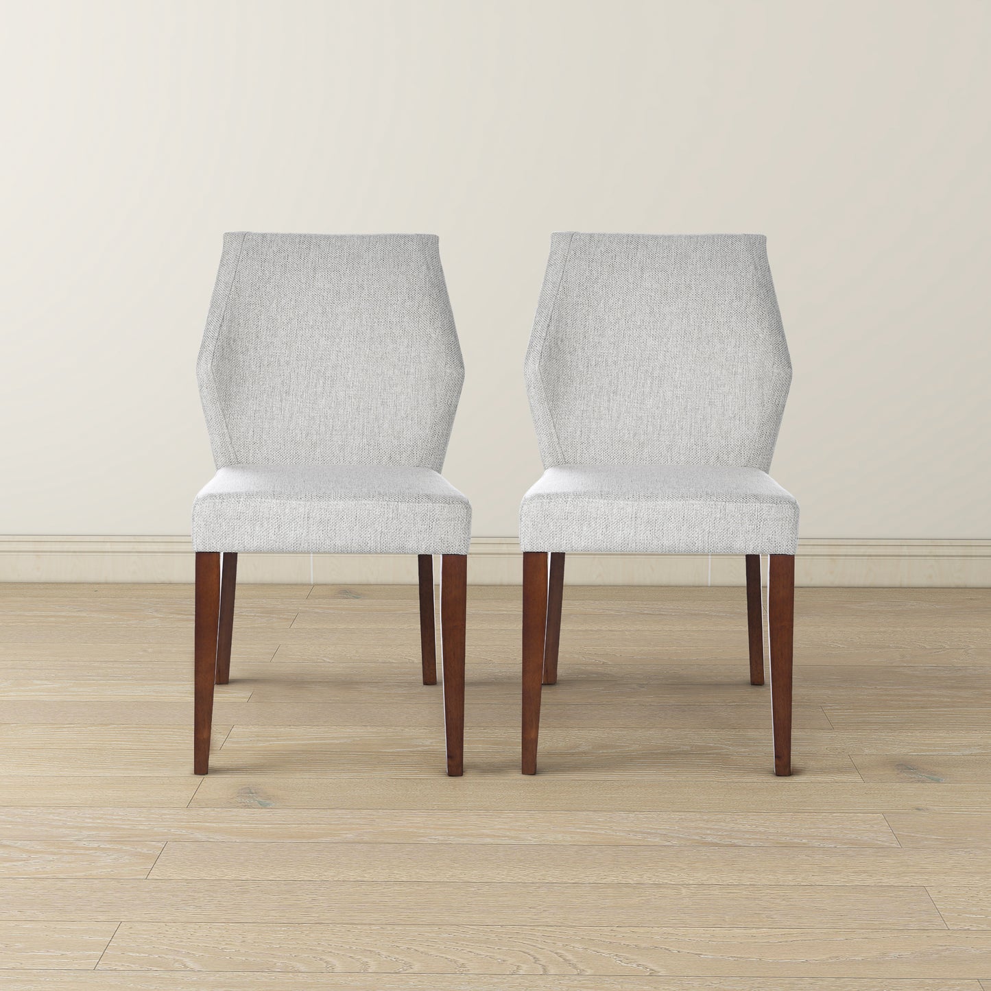 Two light gray upholstered dining chairs with wooden legs