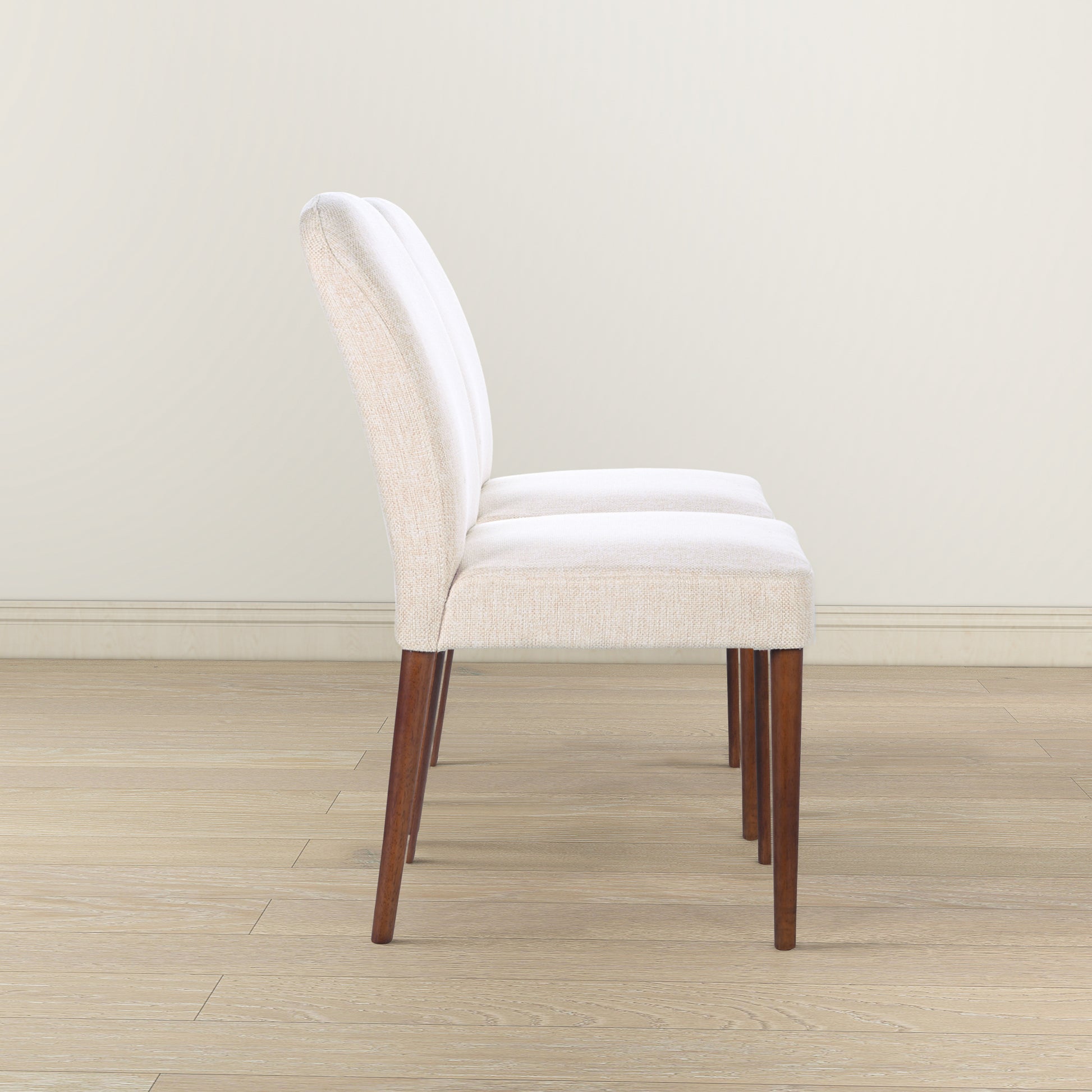 Beige upholstered dining chair with curved back and dark wood legs
