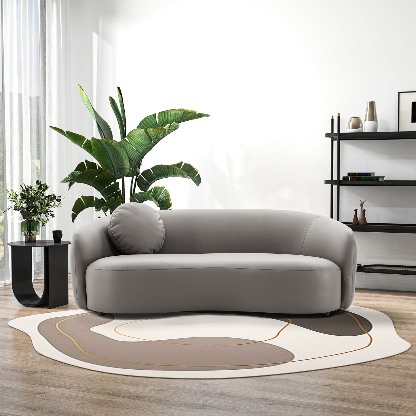 Curved grey fabric sofa with round accent pillow on a modern abstract rug
