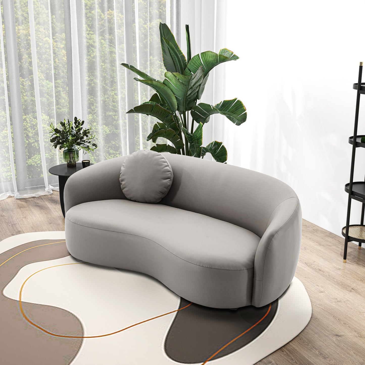 Gray velvet curved sofa with rounded arms and a circular accent pillow