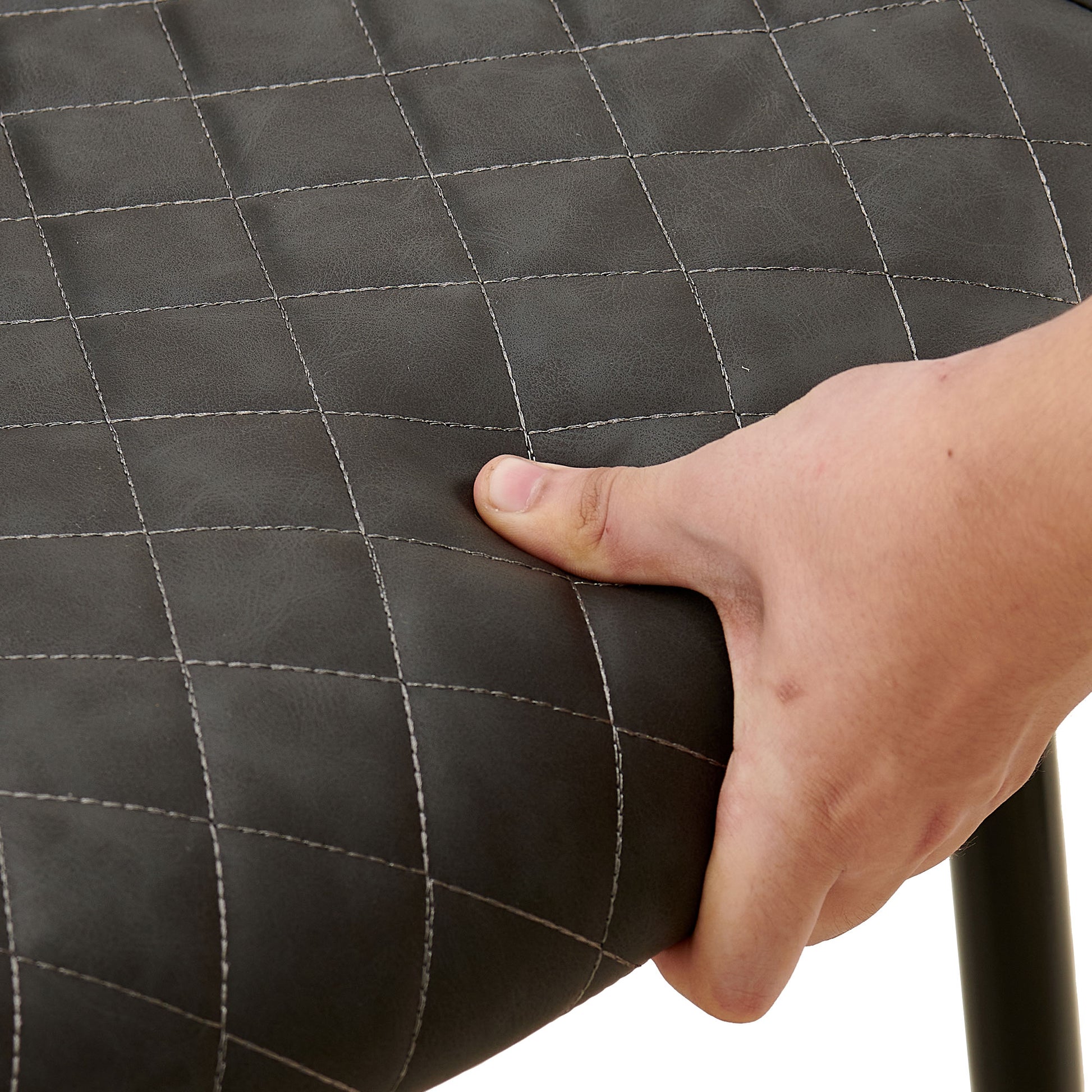 Dark gray diamondstitched faux leather seat cushion with a hand pressing into its softness