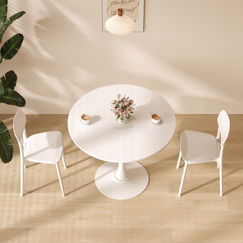 White tulip pedestal dining table with two chairs and flower centerpiece