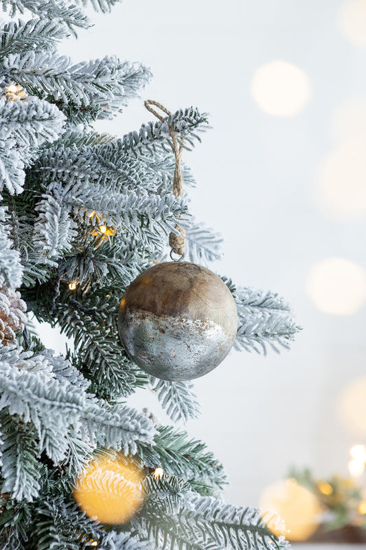 Rustic wooden Christmas ornament with silver distressed finish hanging on flocked tree branch