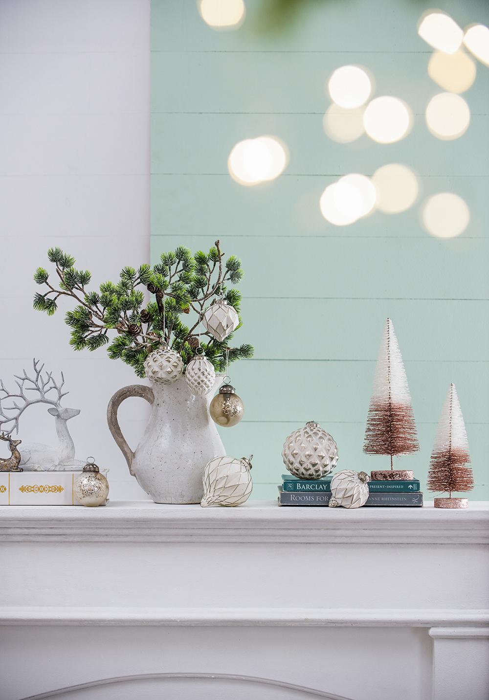 White ceramic pitcher with green pine branches and decorative Christmas ornaments
