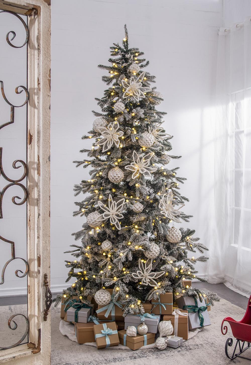 Frosted artificial Christmas tree with warm LED lights and white snowflake ornaments