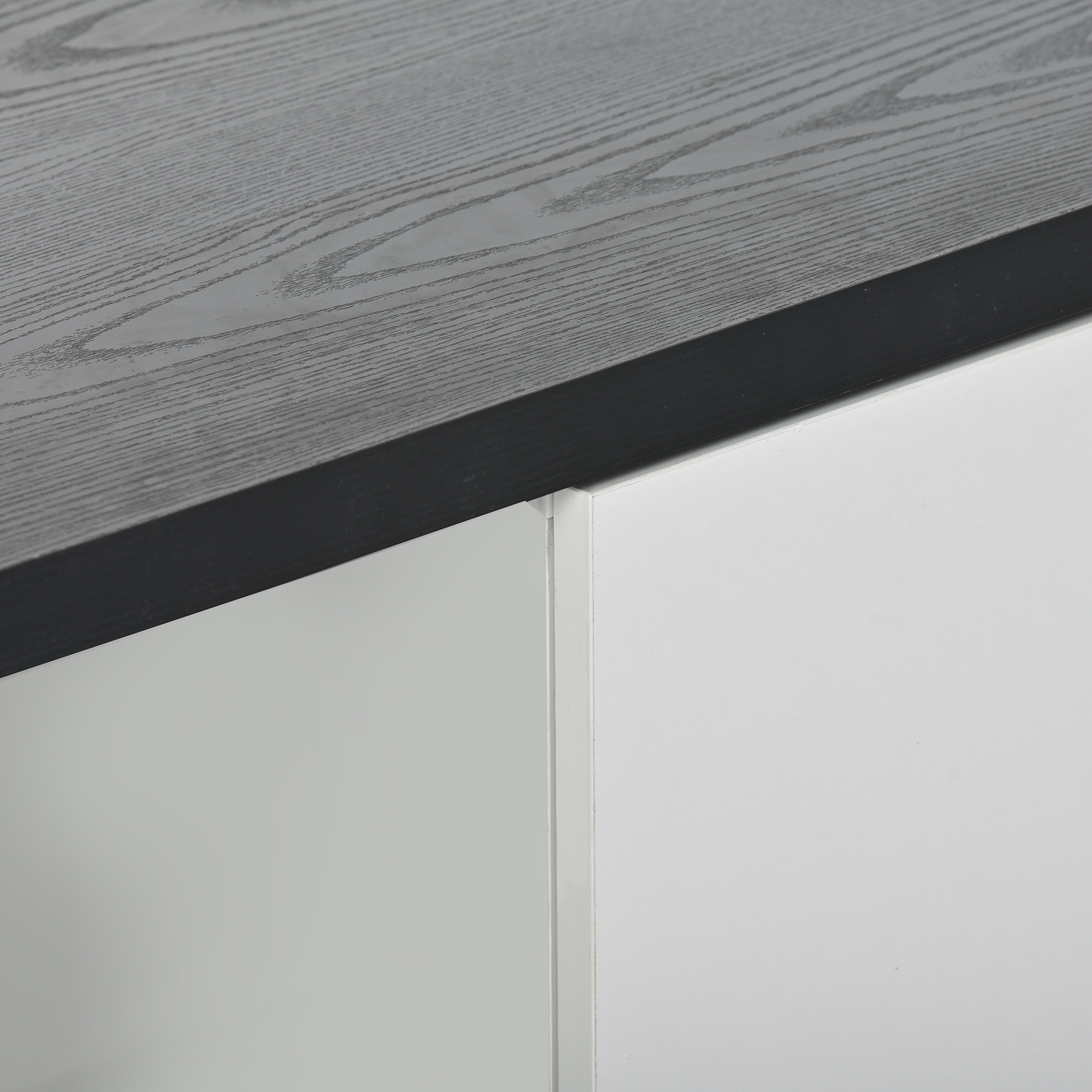 Closeup of dark grey wood grain tabletop with white cabinet panels