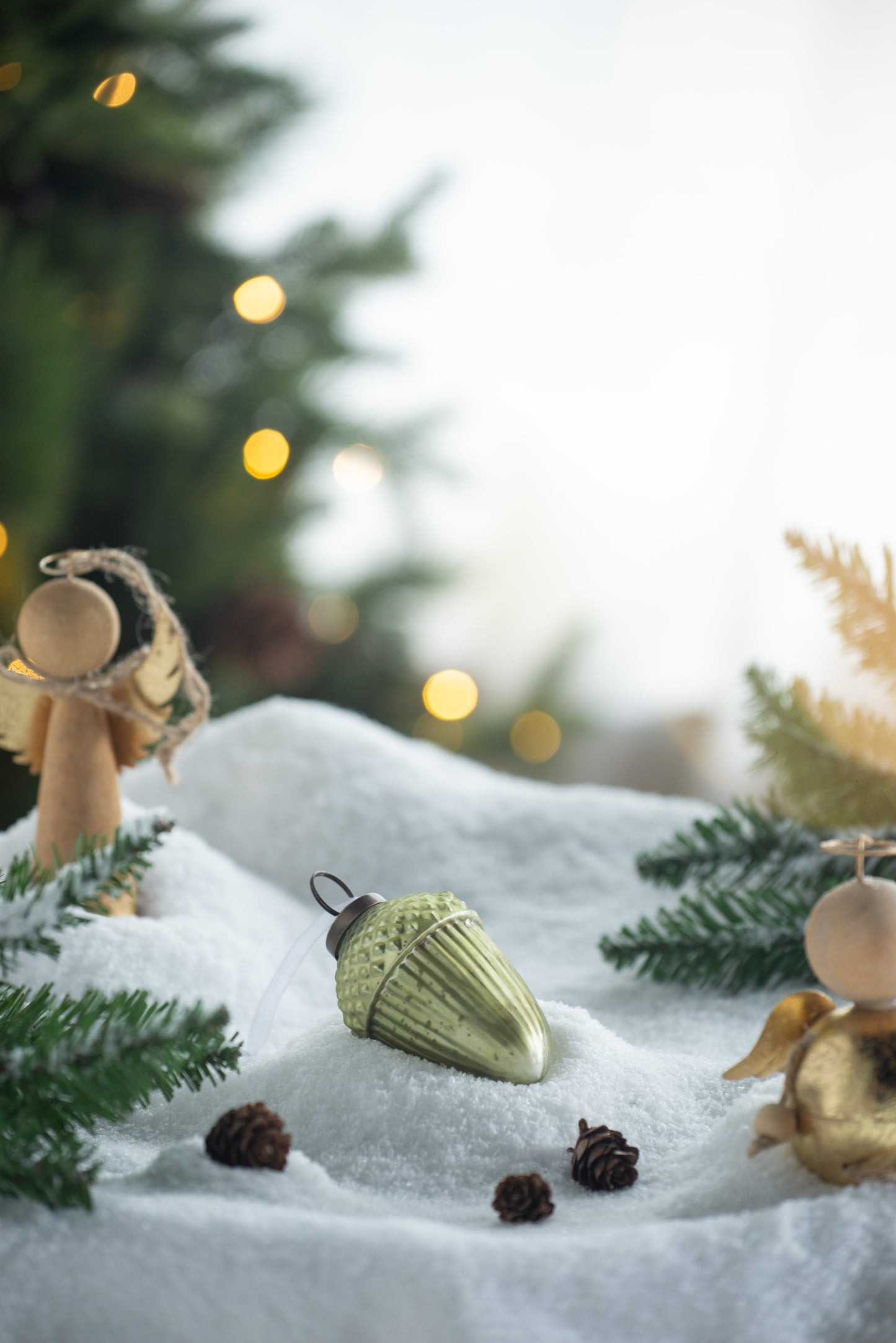 Green glass acorn ornament nestled in faux snow