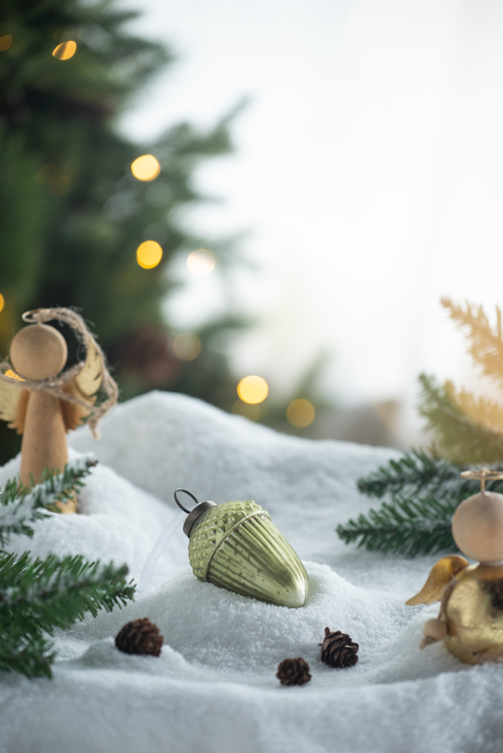 Green glass acorn ornament nestled in faux snow