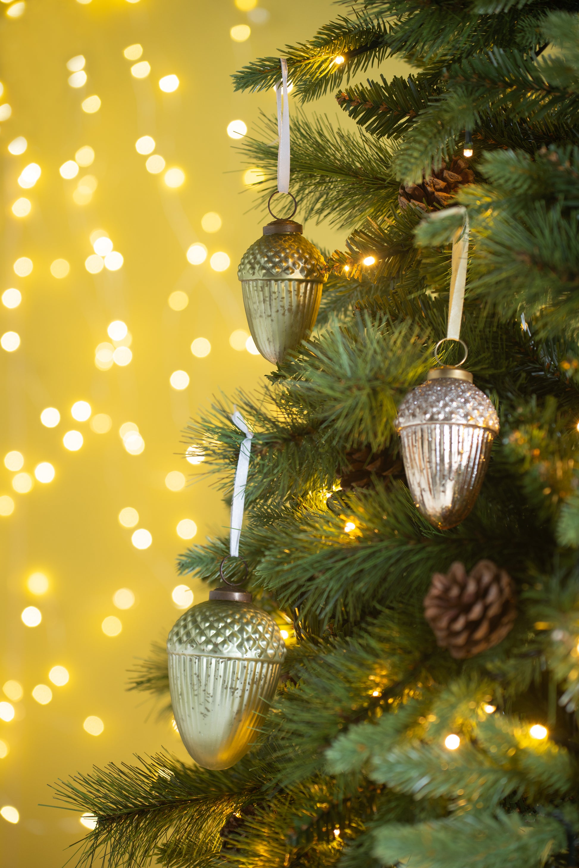Textured gold acorn Christmas ornament hanging on a pine tree branch
