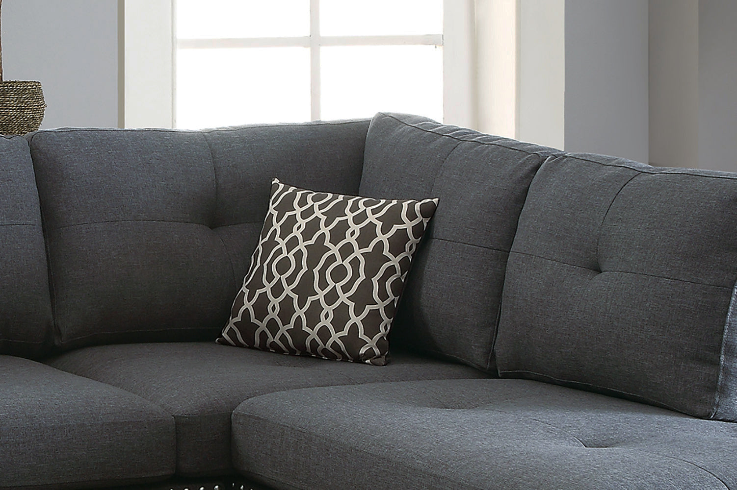 Dark gray sectional sofa with button tufting and a decorative geometric pillow