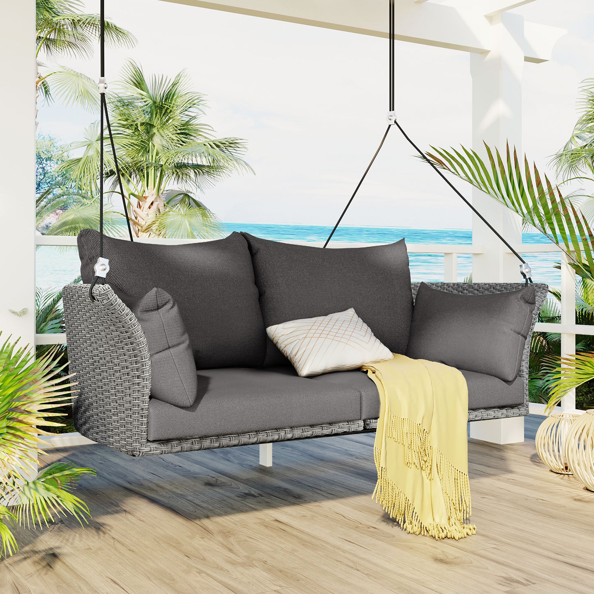 Gray wicker outdoor swing bench with plush cushions and yellow throw