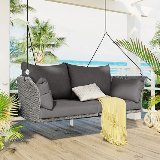 Gray wicker outdoor swing bench with plush cushions and yellow throw