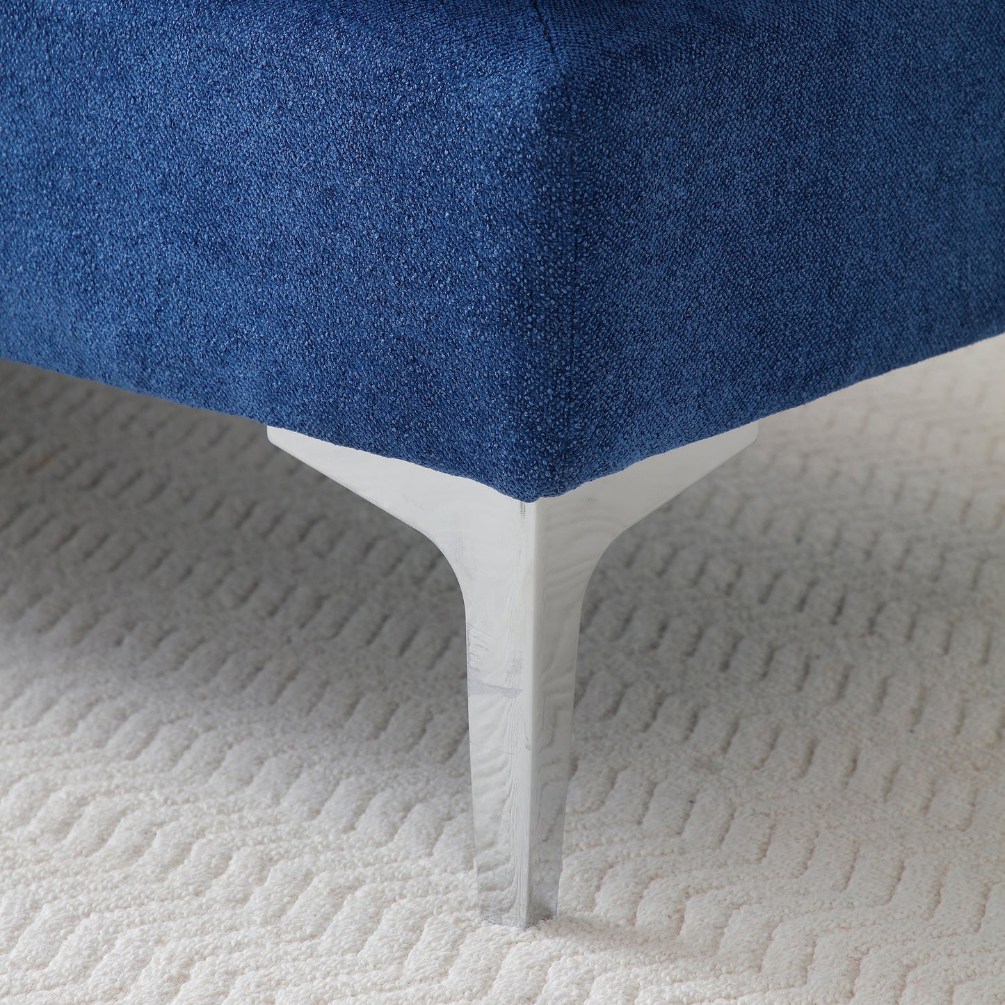 Deep blue textured fabric sofa corner with a modern white woodgrain leg