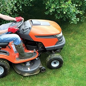 Orange riding lawn mower with large rear wheels cutting green grass