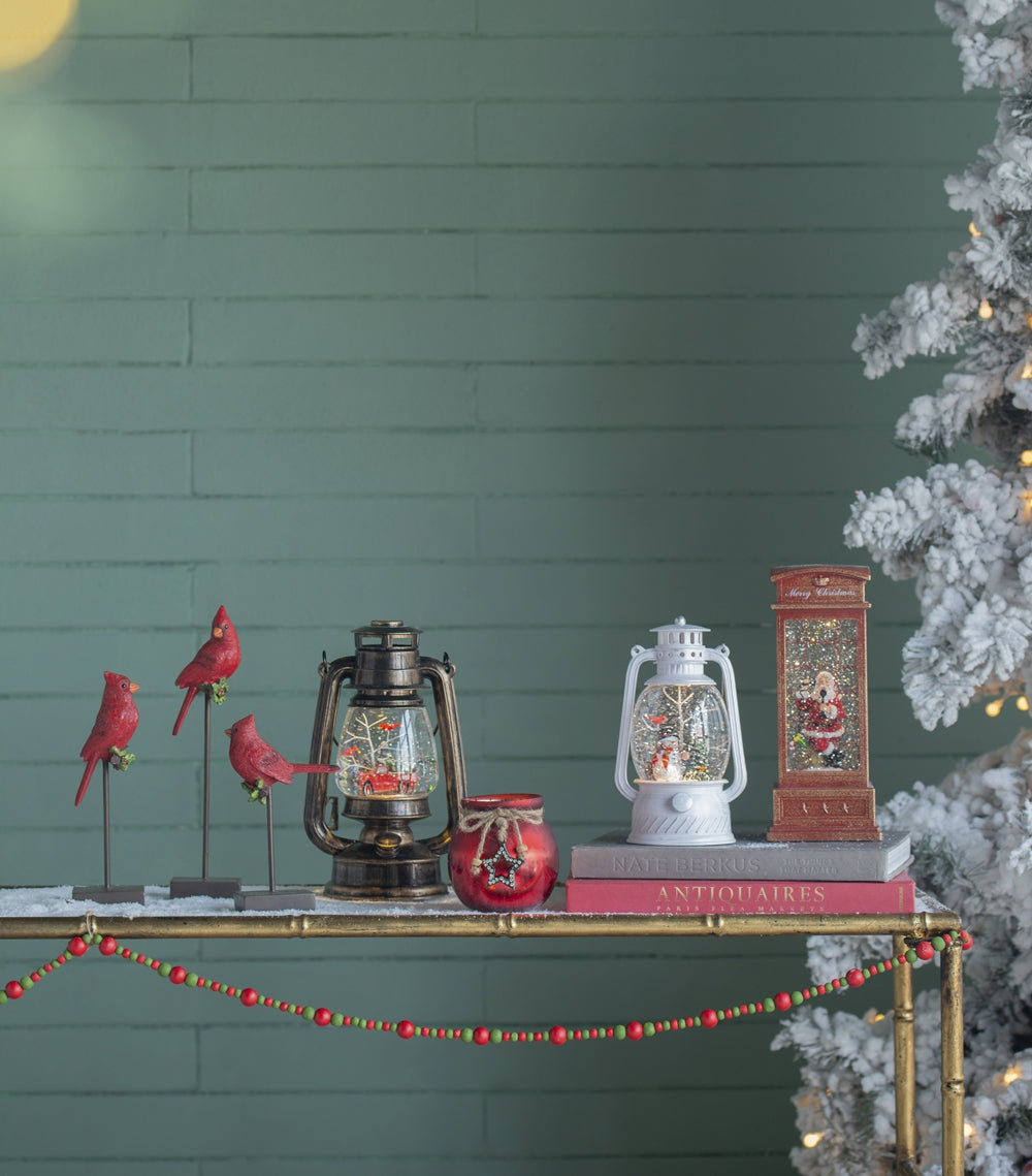 Three red cardinal figurines perched on stands
