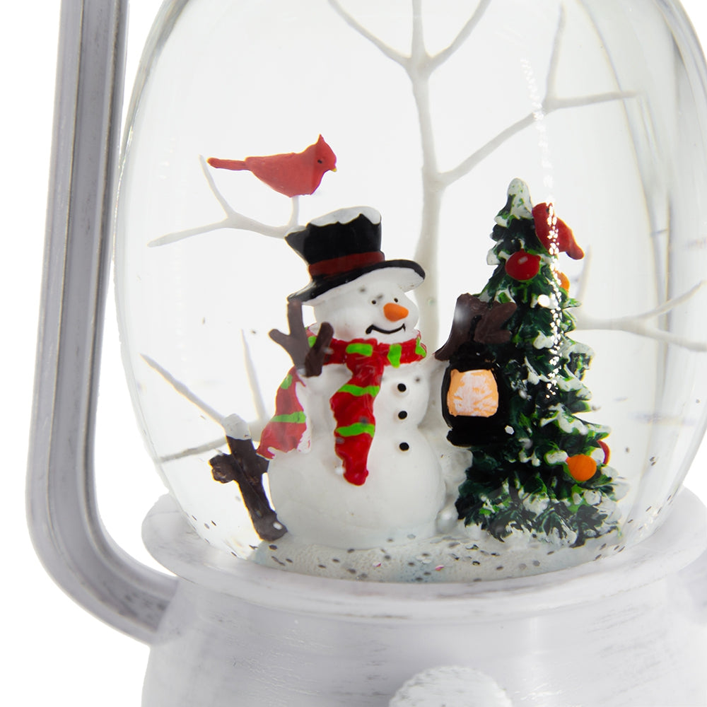 Snow globe featuring a snowman with a red and green scarf holding a lantern