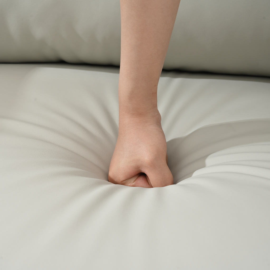Closeup of a hand pressing into a soft white cushioned sofa for comfort test