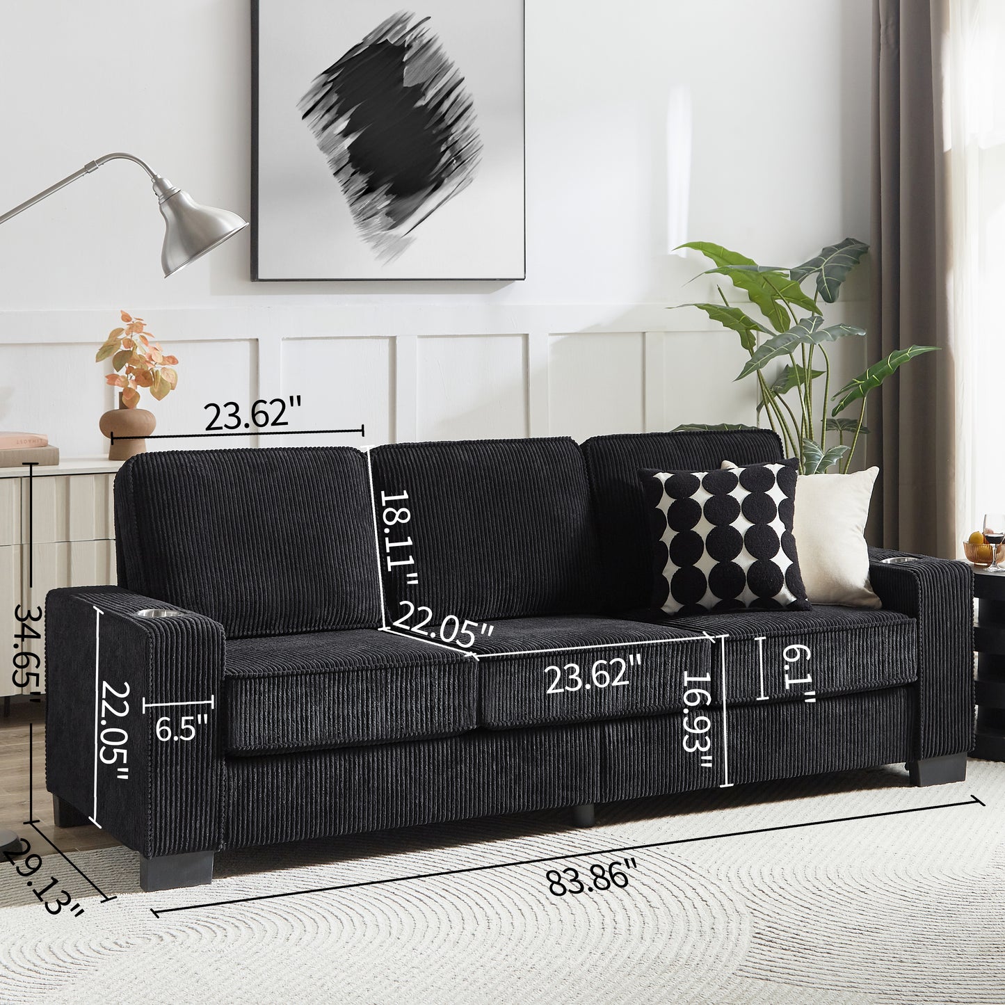 Black corduroy sofa with integrated cup holders and accent pillows on a textured rug