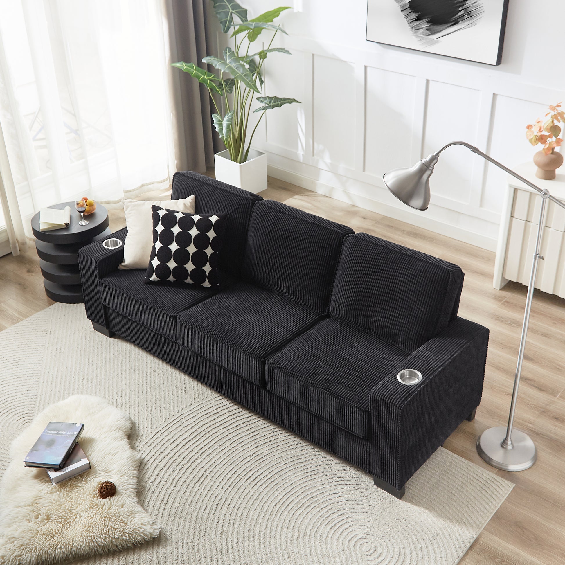 Black corduroy sofa with plush cushions and builtin cup holders