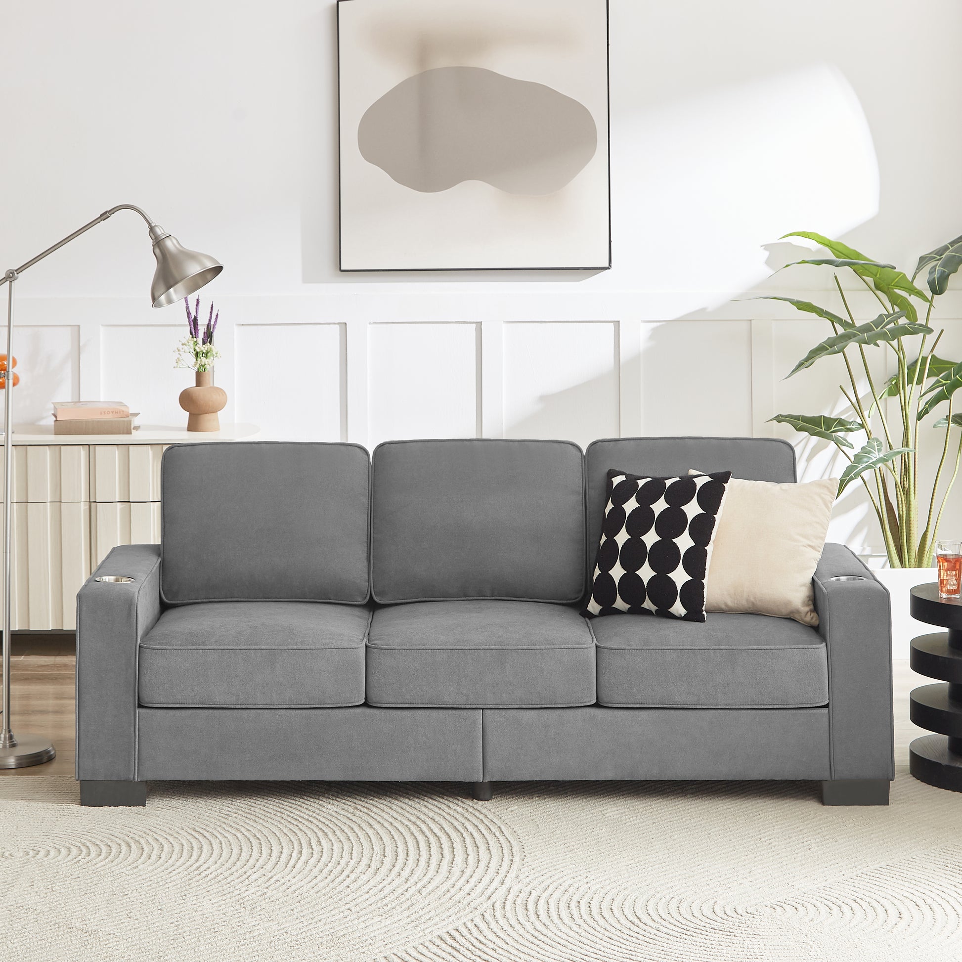 Grey fabric sofa with builtin cup holders and modern black accent pillow