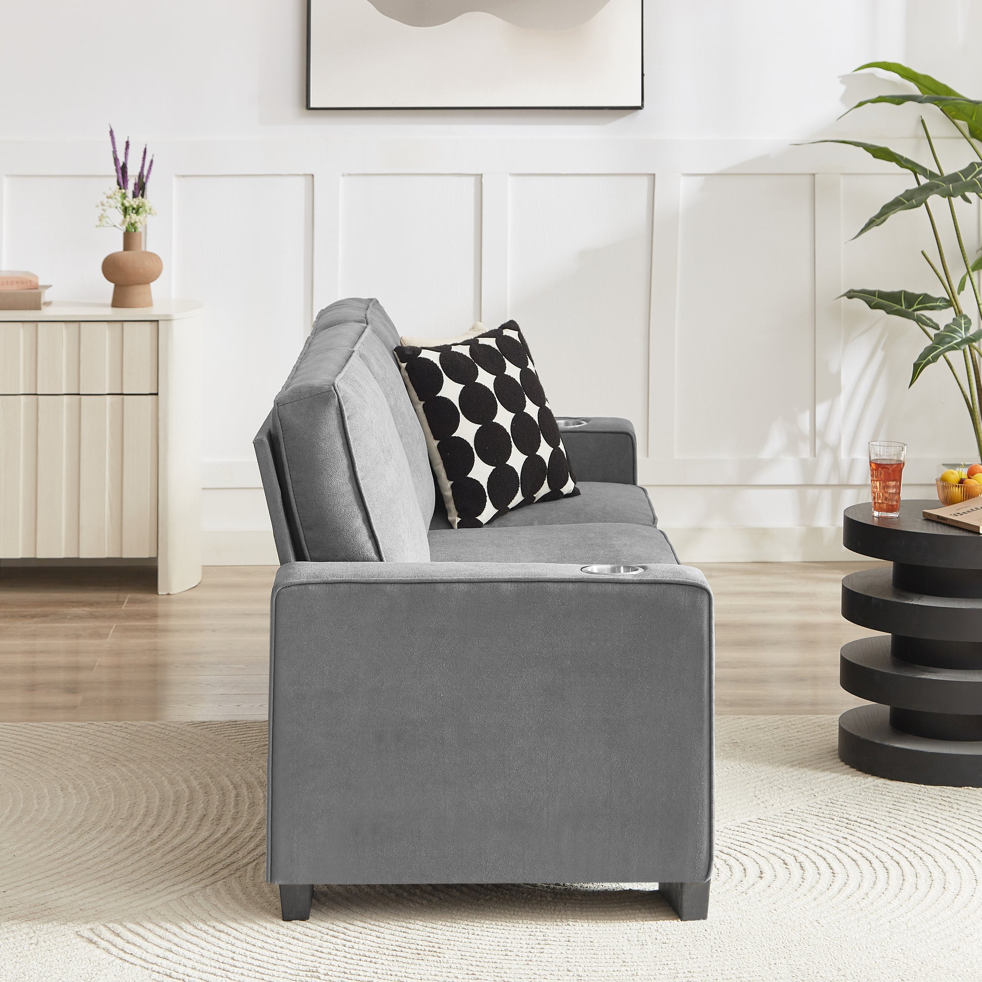 Gray velvet sofa with cup holders and a patterned accent pillow