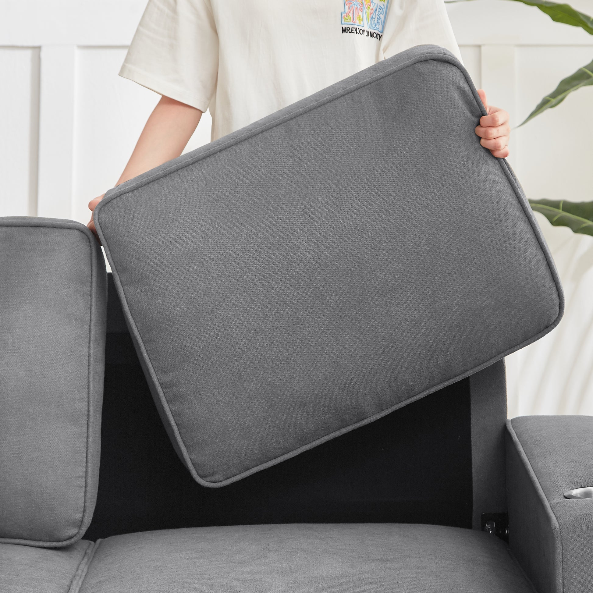 Gray fabric sofa cushion being lifted to reveal storage compartment
