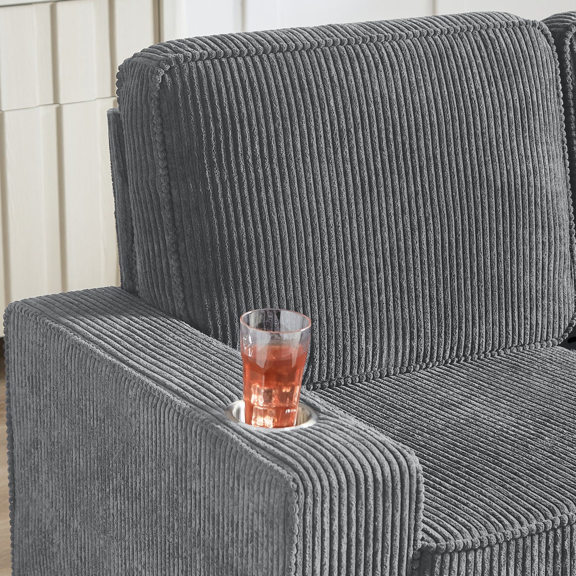 Grey corduroy sofa armrest with builtin cup holder and drink