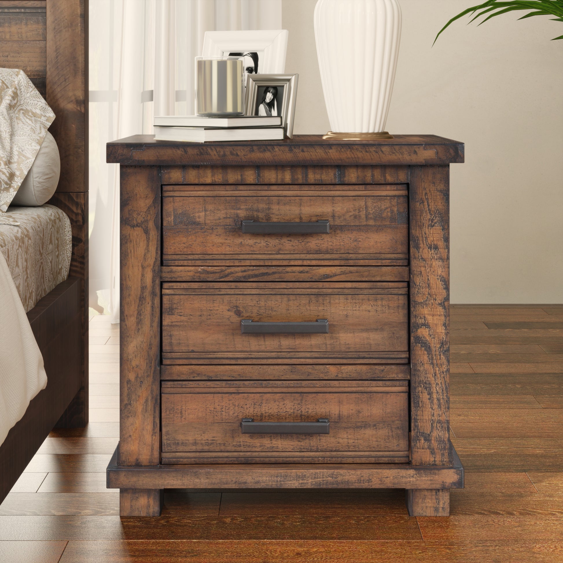 Rustic brown wood bedside table with three drawers and dark metal hardware