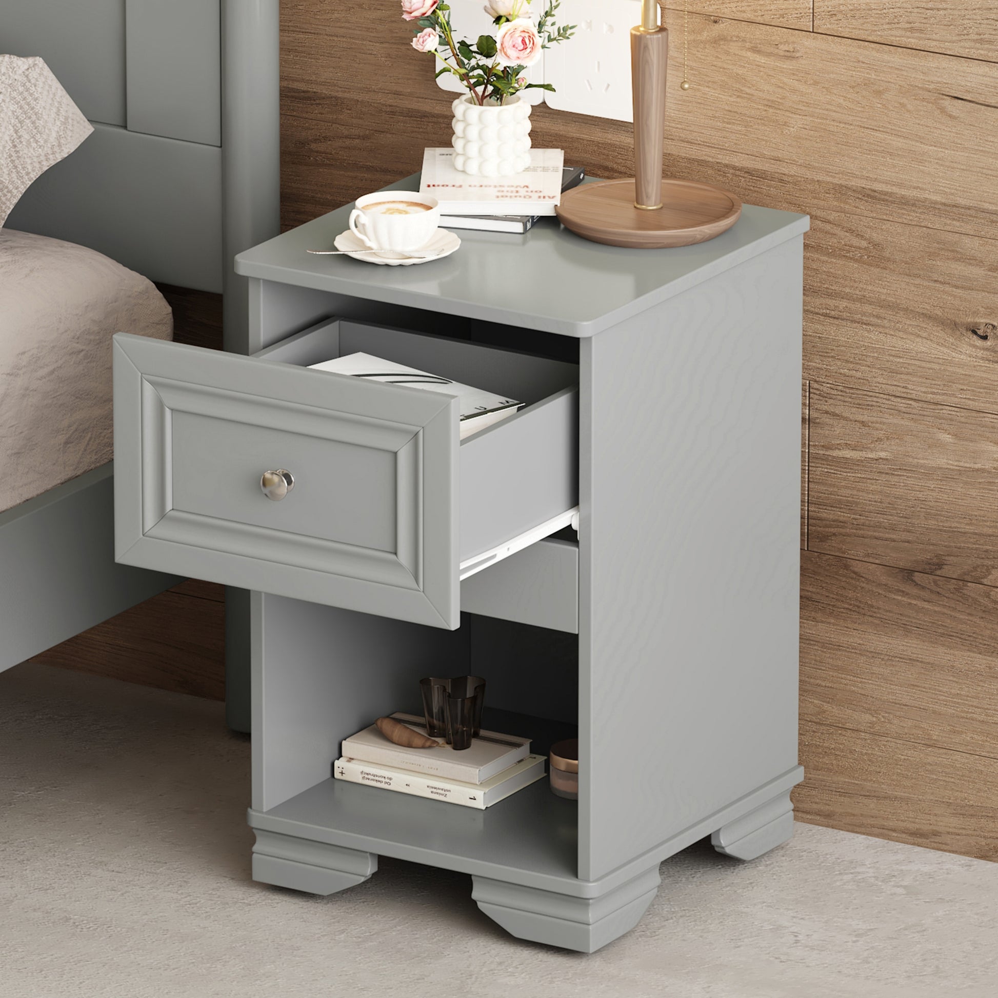 Gray painted wood bedside table with open drawer and decor