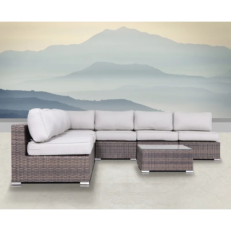 Gray wicker sectional sofa with white cushions and glasstop coffee table