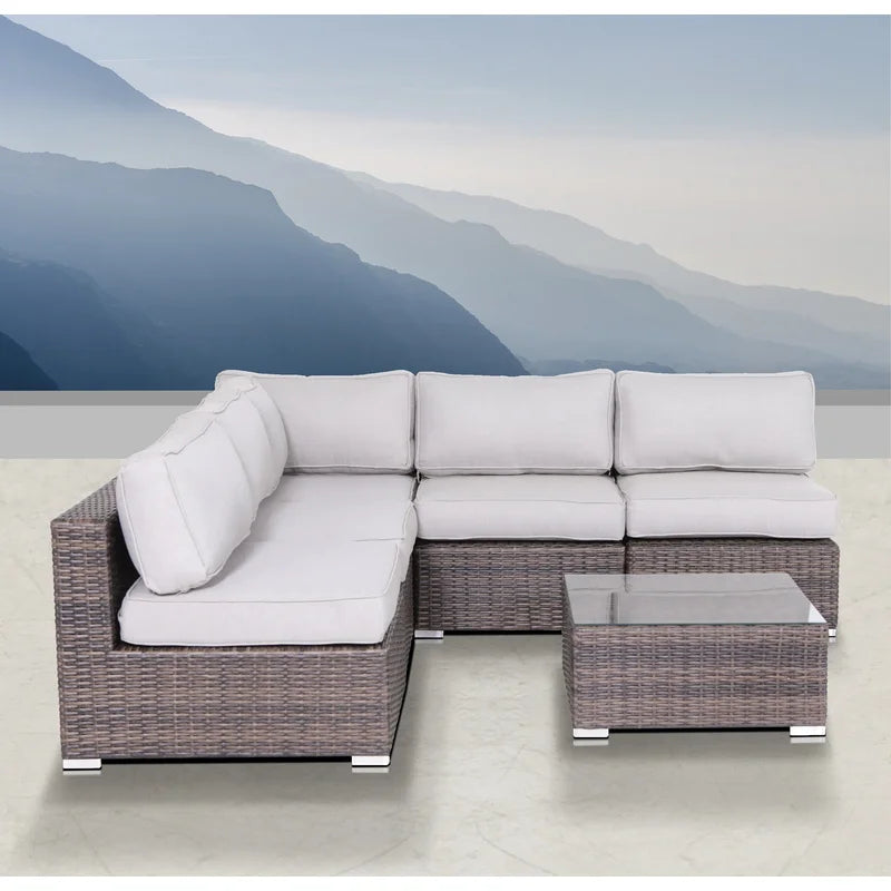 Gray wicker sectional sofa with white cushions and glass top coffee table