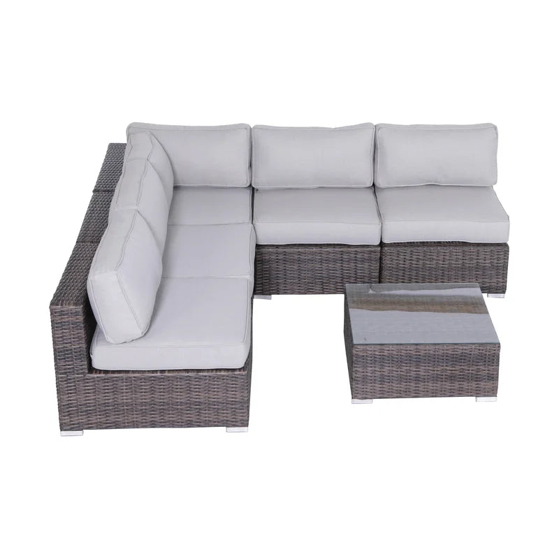 Grey wicker sectional sofa with plush cushions and a matching coffee table