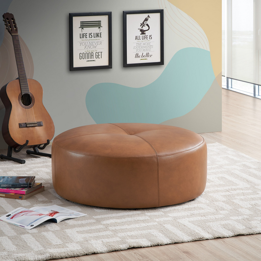 Round camelcolored leather ottoman with tufted top and clean stitching perfect for living room accent