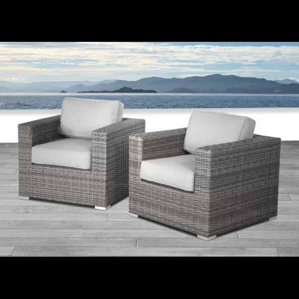 Grey wicker armchairs with white cushions on a wooden deck