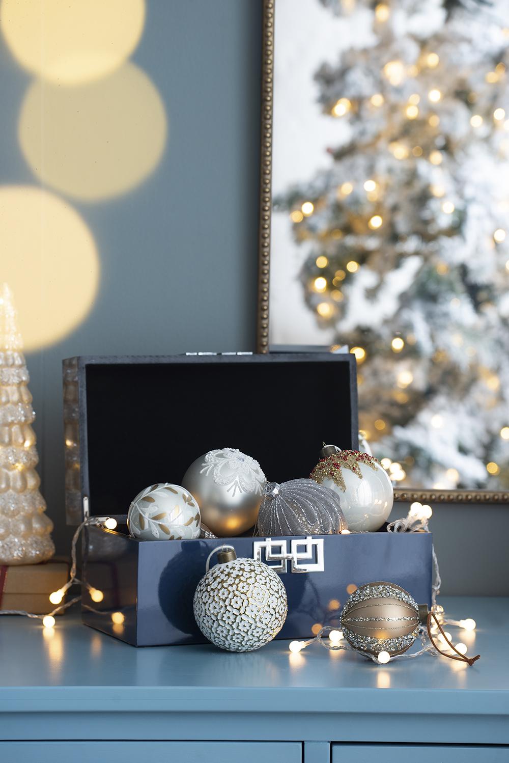 Assortment of festive Christmas ornaments in a navy blue box with fairy lights