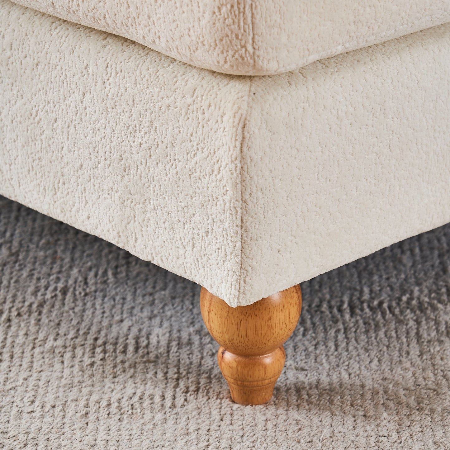 Cream boucle fabric sofa corner with turned wooden leg on grey rug