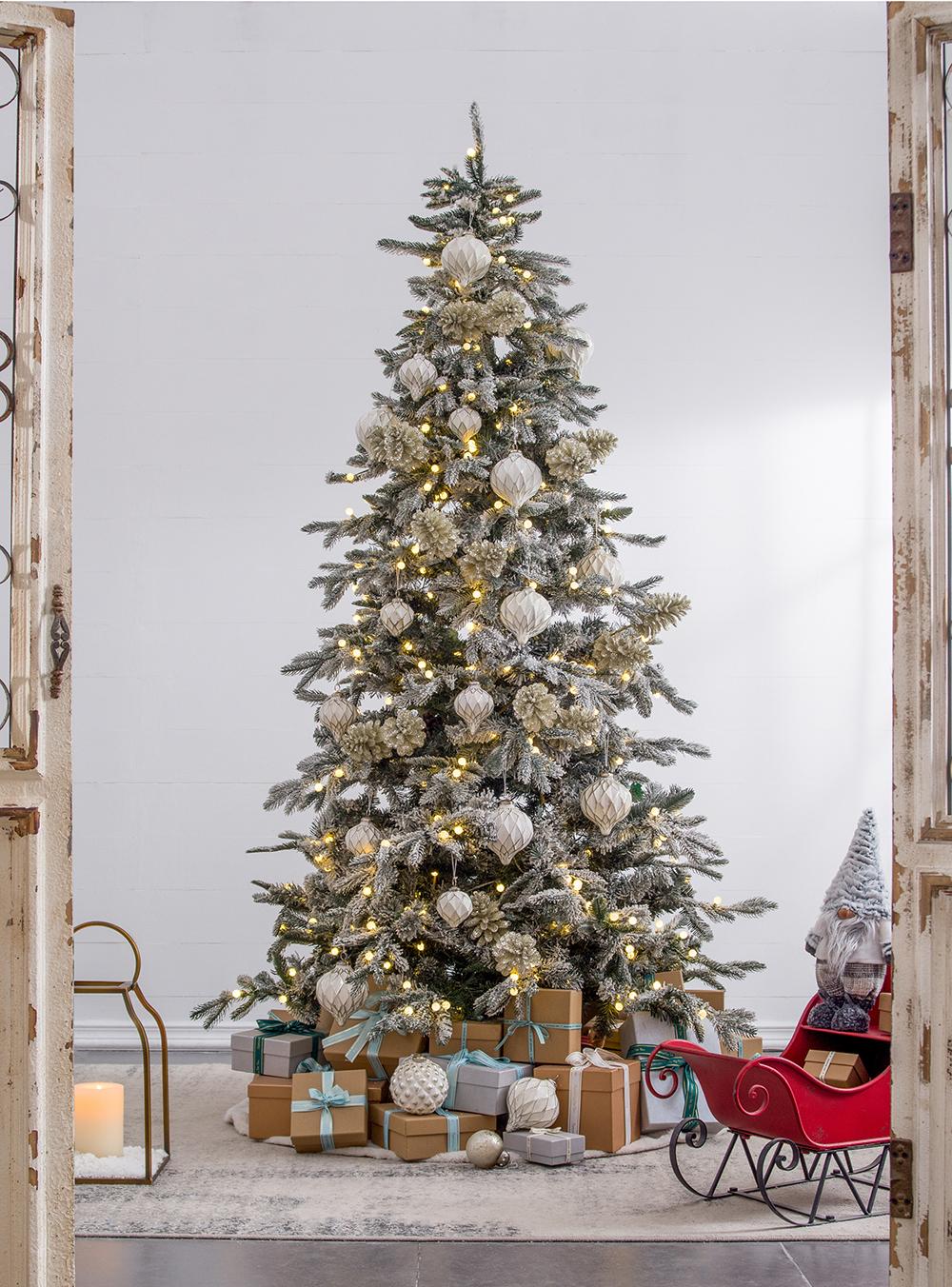 Flocked artificial Christmas tree with white and gold ornaments and warm LED lights