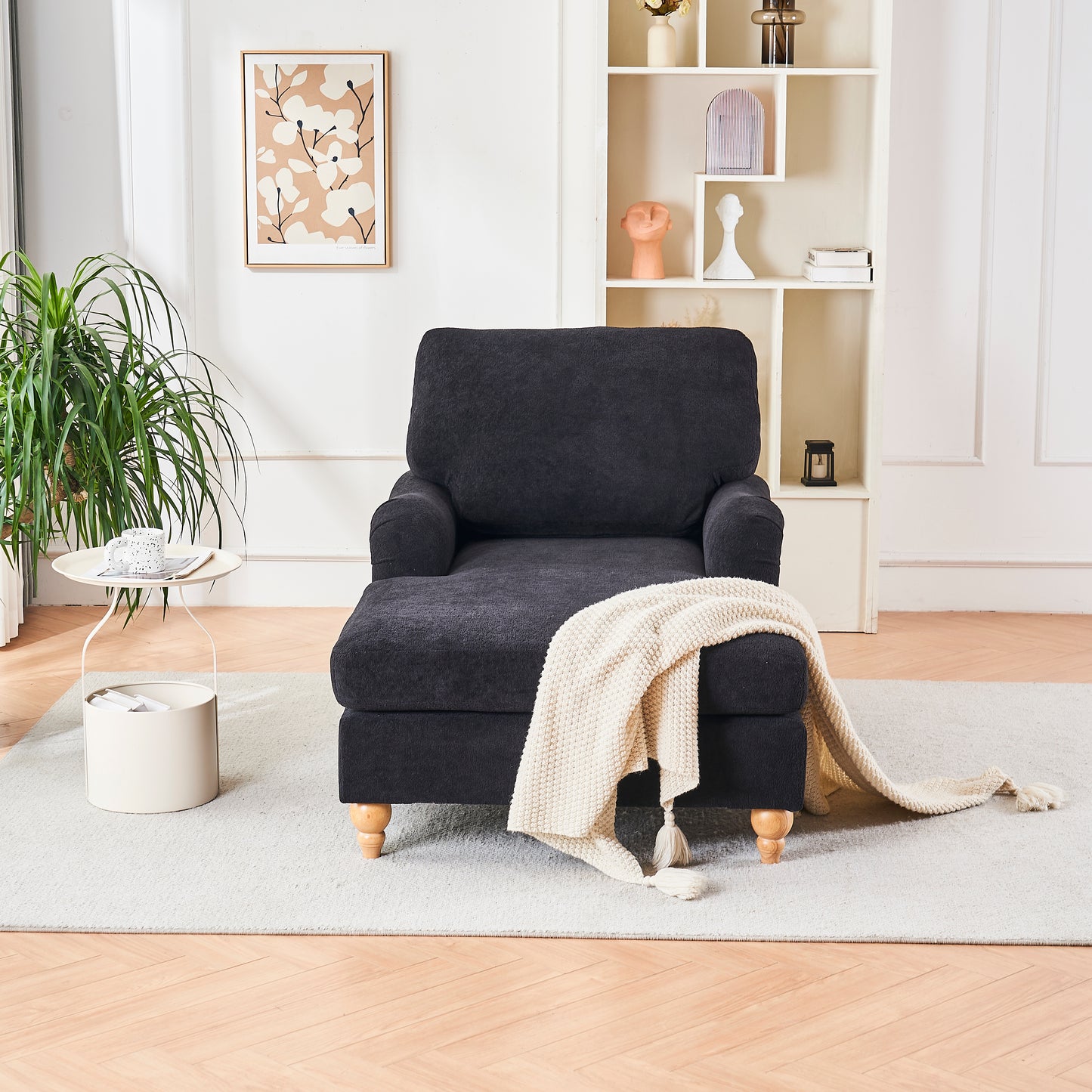 Plush dark gray chaise lounge with natural wood legs and a cream throw blanket